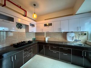 a kitchen with white cabinets and black counter tops at Villa Vista With Swimming Pool in Lucknow