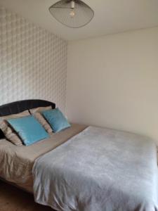 Un dormitorio con una cama grande con almohadas azules. en La Maison du Verger avec Jardin, en Carnac 10 fotos más