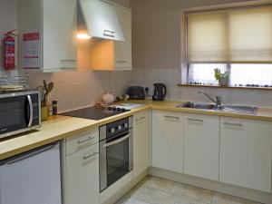 a kitchen with white cabinets and a microwave at Clougha View - 29531 in Scotforth