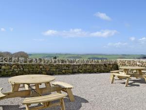 three picnic tables sitting next to a stone wall at Clougha View - 29531 in Scotforth