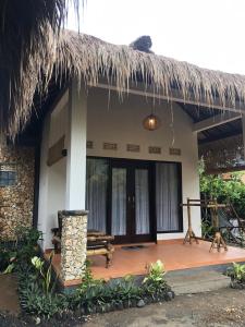 uma casa com um telhado de palha e um alpendre de madeira em Cewin's Homestay em Kuta