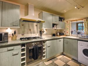 a kitchen with gray cabinets and a stove top oven at Coach House in Ratho