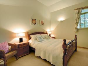 a bedroom with a large bed and a chair at Coach House in Ratho