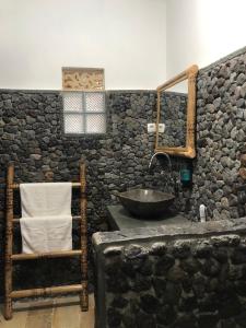 un bagno in pietra con lavandino e parete in pietra di Cewin's Homestay a Kuta Lombok