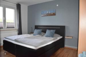 1 dormitorio con 1 cama grande con sábanas blancas y almohadas azules en Ferienhaus mit Garten in Nordseenähe, en Langenhorn