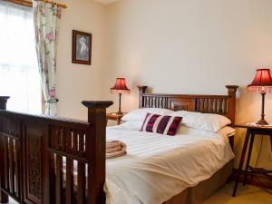 1 dormitorio con cama de madera, 2 lámparas y ventana en Ty Nain en Tywyn