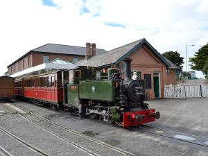 a green and red train parked at a train station at Ty Nain in Tywyn