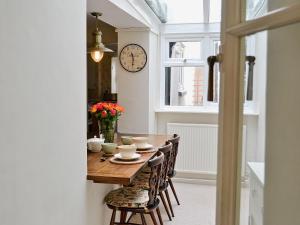 a dining room table with chairs and a clock on the wall at Midships in Instow