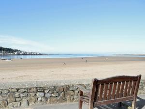 a wooden bench sitting on the beach near a stone wall at Midships in Instow