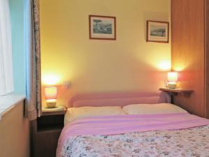 a bedroom with a pink bed with two lamps at Cliff End in Freshwater