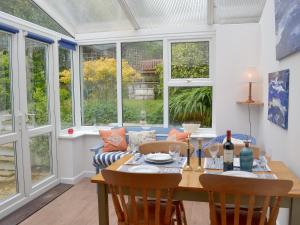 a dining room with a table and chairs and windows at Trecarian in Port Isaac