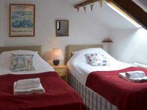 two beds in a room with red sheets and towels at Trecarian in Port Isaac