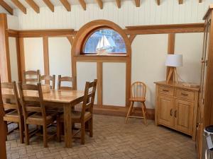 a dining room with a wooden table and a window at The Coach House in Hemsby