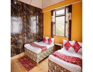 two beds in a room with yellow walls at Hill Home Stay, Mankhim Road, Aritar, Sikkim in Aritar