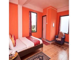 a bedroom with orange walls and a bed and a chair at Hill Home Stay, Mankhim Road, Aritar, Sikkim in Aritar