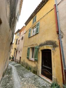 un vicolo in un vecchio edificio con una porta di Petit cocon au cœur du centre historique a Biot