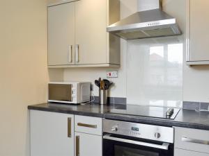 a kitchen with white cabinets and a microwave and a stove at Mews Cottage in Bridlington