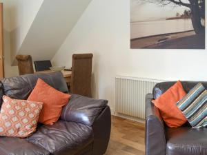 a living room with two leather couches with orange pillows at Mews Cottage in Bridlington