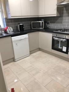 a kitchen with white cabinets and a tile floor at Glory House in Ilford