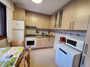 uma cozinha com electrodomésticos brancos e uma mesa em Acogedor apartamento en Silgar em Sanxenxo