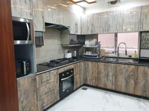 a kitchen with wooden cabinets and a stove top oven at White House Executive - Guest House Islamabad in Rawalpindi