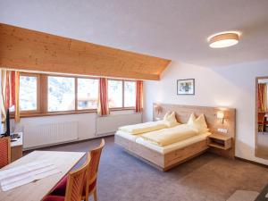 a bedroom with a bed and a table and some windows at Apart Agnes in Obergurgl