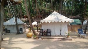 a white tent with a chair and a table and chairs at Cola Beach Exclusive Resort in Cola