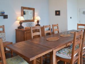 een houten eettafel met stoelen en een spiegel bij Seacliff Cottage in Strete