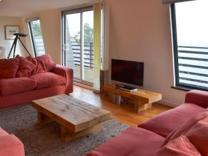 a living room with a red couch and a tv at Seacliff Cottage in Strete