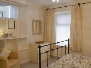 a bedroom with a bed and a chair and a window at Seacliff Cottage in Strete