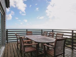 a wooden table and chairs on a deck with the ocean at Seacliff Cottage in Strete