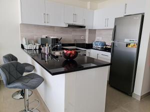 a kitchen with a black refrigerator and white cabinets at Cozy Furnished Studio in Abu Dhabi