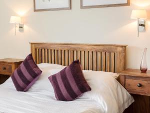 łóżko z dwoma fioletowymi poduszkami na górze w obiekcie The Old Dairy w mieście Cam