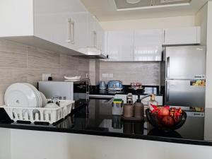 a kitchen with white appliances and a black counter top at Cozy Furnished Studio in Abu Dhabi