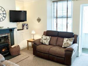 a living room with a brown couch and a tv at Harbour Watch in Charlestown