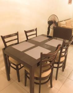 a dining room table with two chairs and a fan at Homey Unit in Alabang in Manila