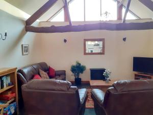 a living room with two leather chairs and a tv at The Barn in Talsarnau