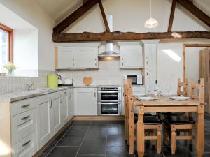 a kitchen with white cabinets and a wooden table at The Barn in Talsarnau