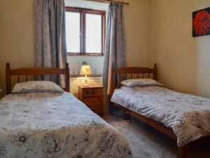 two twin beds in a room with a window at The Barn in Talsarnau