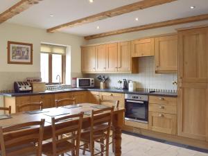 una cocina con armarios de madera y una mesa con sillas. en Pentre Cottage, en Ferryside