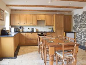 una cocina con armarios de madera y una mesa y sillas de madera. en Pentre Cottage, en Ferryside