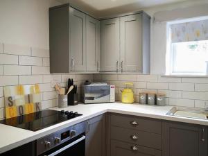 a kitchen with white cabinets and a sink and a microwave at Oak Barn in Porthtowan