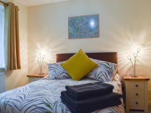 um quarto com uma cama com uma almofada amarela e 2 candeeiros em Rose Corner em Countess Wear