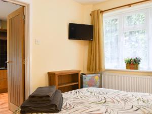 a bedroom with a bed and a window and a television at Rose Corner in Countess Wear