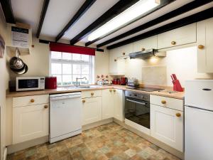 a kitchen with white cabinets and white appliances at Barmstone Cottage in Brancaster