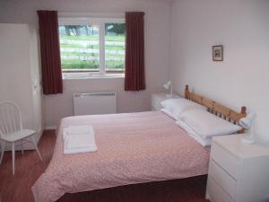 a bedroom with a bed and a chair and a window at Fell Croft in Pooley Bridge