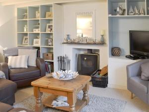 a living room with a table and a fireplace at Gumburnville in Lanteglos