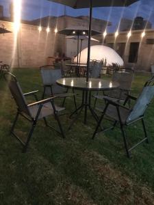 a table and chairs with an umbrella in the grass at Hostal Nahui Meztli in San Juan Teotihuacán