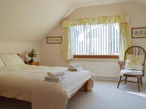 a bedroom with a bed and a chair and a window at Burnside in St. Andrews