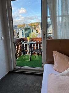 a bedroom with a door open to a balcony with a table at Sevda's Hotel Garni Weinforth in Willingen